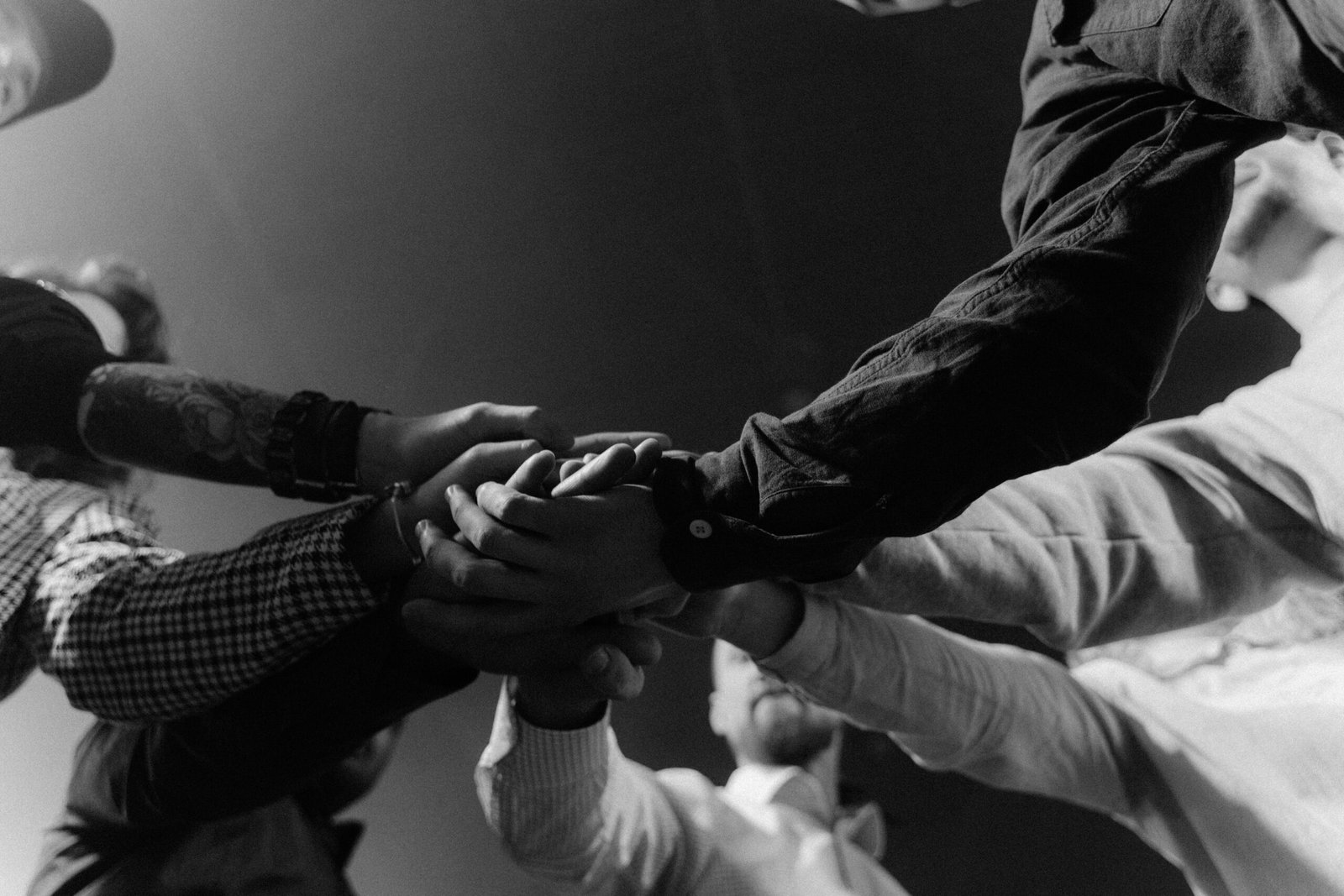 A group of diverse hands united in a gesture of teamwork and collaboration.