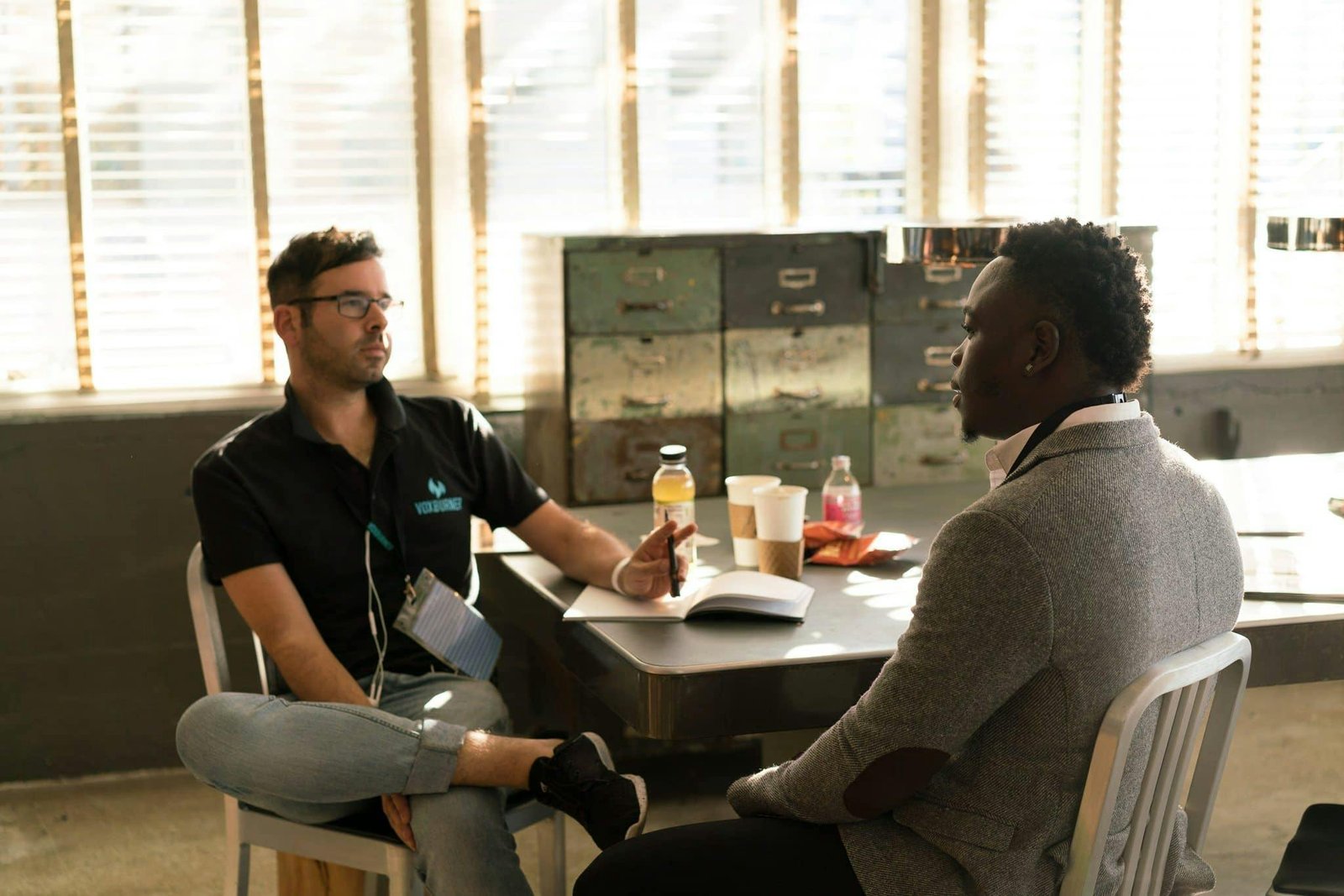 Two men having a focused business discussion in a sunlit office space.